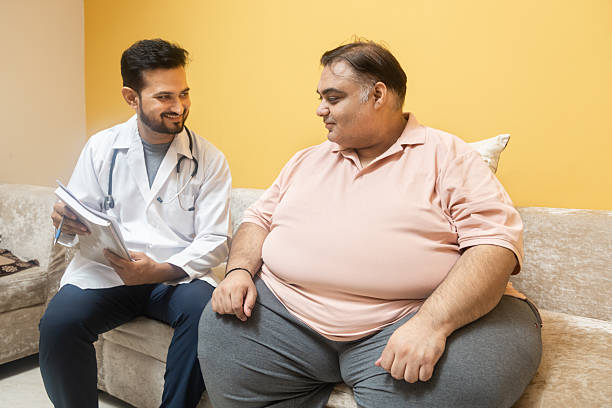 Male indian doctor consulting with overweight patient. Healthcare worker advice obese man to lose weight and discuss health risks of overweight. Obesity and Diabetes.